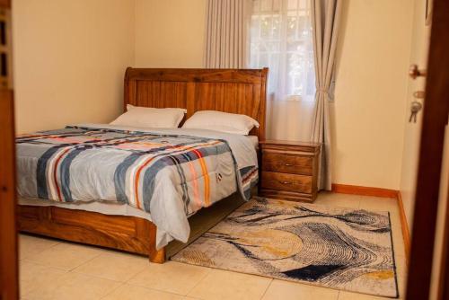a bedroom with a bed and a window and a rug at Blissful Homes in Kampala