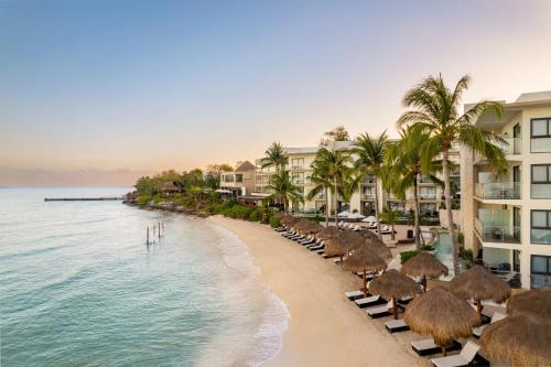 a beach with chairs and palm trees and buildings at Dreams Cozumel Cape Resort & Spa in Cozumel