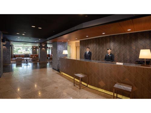 two men standing at a counter in a hotel lobby at Hotel Flags Isahaya - Vacation STAY 25613v in Isahaya