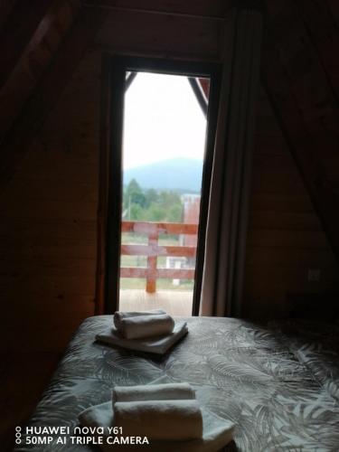 a bed in a room with a window with towels on it at Vila Dajana Zminica in Žabljak