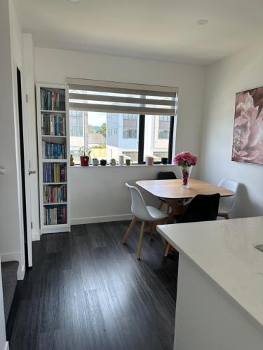 sala de estar con mesa, sillas y estante para libros en George townhouse, en Auckland