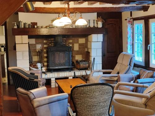 a living room with chairs and a fireplace at Gîte Le Clos Maridor - Grande Longère Normande -15 personnes in Saint-Martin-Saint-Firmin