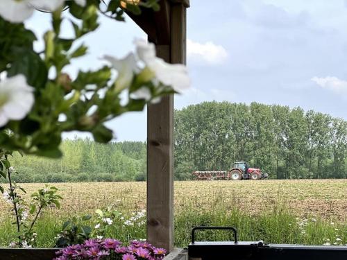a tractor in the middle of a field at Square Shaped Farmhouse from 1713 in Nieuwenhove