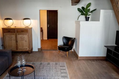 a living room with a couch and a table and a chair at Square Shaped Farmhouse from 1713 in Nieuwenhove