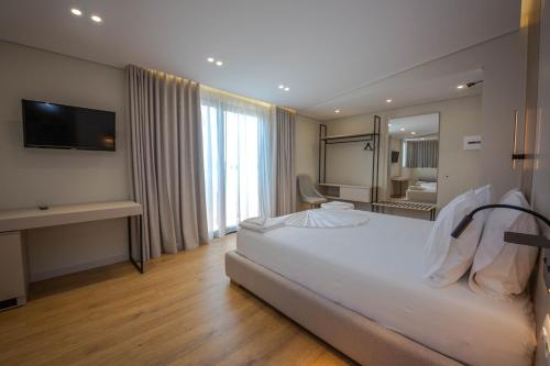 a bedroom with a large white bed and a television at Hotel Vista Mare in Ksamil