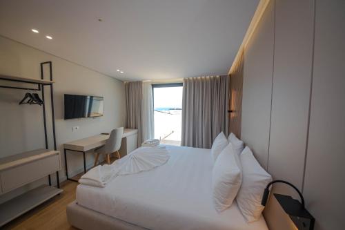 a hotel room with a bed and a desk and a window at Hotel Vista Mare in Ksamil