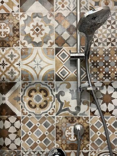 a bathroom with a shower head and a tile wall at Vinicio's House in Carmignano