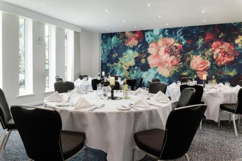 a conference room with tables and chairs and a floral wall at Holiday Inn South Normanton M1, Jct.28 by IHG in South Normanton