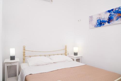 a white bedroom with a bed and two white tables at Akrogiali Pension in Platis Yialos Sifnos
