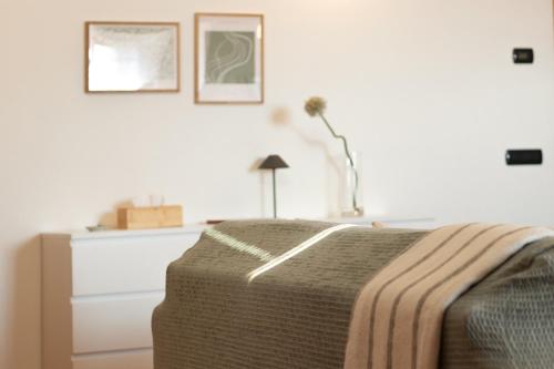 a bedroom with a bed and a dresser with a blanket at La Torretta "I Gabbiani" sul Lago Maggiore in Maccagno Inferiore