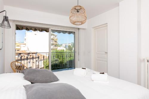 une chambre blanche avec un lit et une grande fenêtre dans l'établissement Hekla, à Cannes