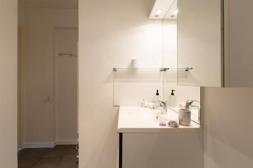 une salle de bain blanche avec un lavabo et un miroir dans l'établissement Hekla, à Cannes