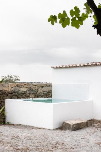 a white building with a stone wall at Monte dos Coureleiros in Castelo de Vide