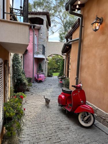 a red scooter parked in an alley with a cat at Guestlands Italia B&B in Arcadia