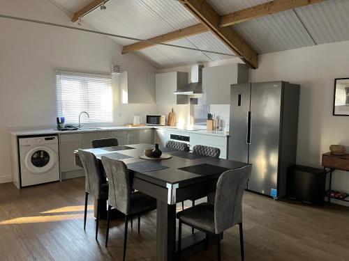a kitchen with a table and chairs and a refrigerator at 3 Bed Barn in Cambridge next to Anglesey Abbey in Cambridge