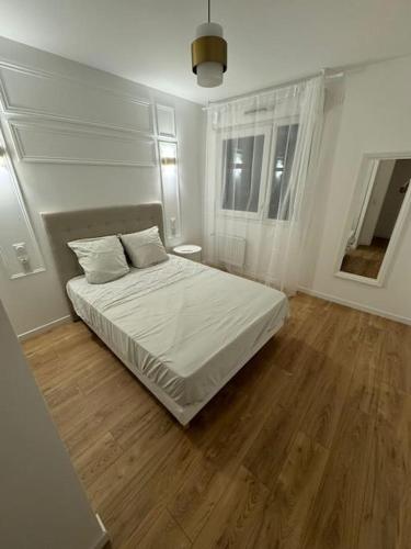Un dormitorio con una cama blanca y suelo de madera. en T4 de 87m2 à 5min de Paris, en Villejuif