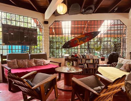 a room with a couch and a surfboard on the wall at La Ruka Hostel in Puerto Viejo