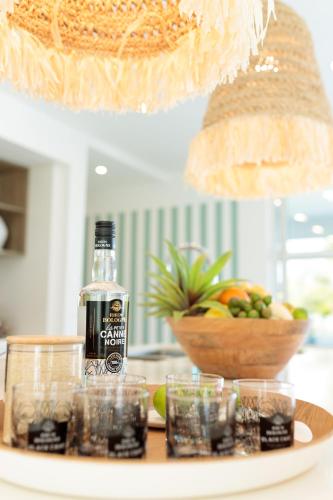 a bottle of alcohol on a table with a bowl of fruit at Hill Rock villas - Blue Silver in Petit-Bourg