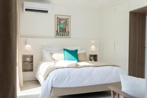 a white bedroom with a large bed with blue pillows at Hill Rock villas - Blue Silver in Petit-Bourg