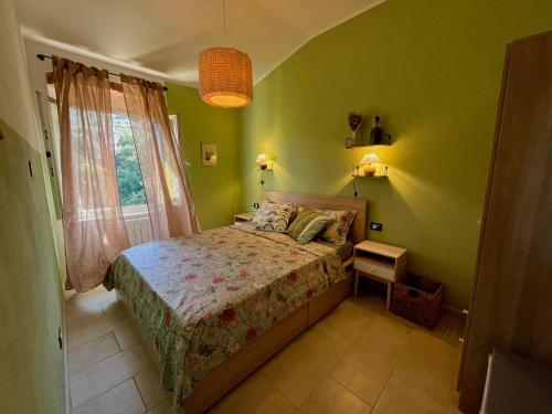 a bedroom with a bed with green walls and a window at Casa Olive 53 Mare in La Spezia