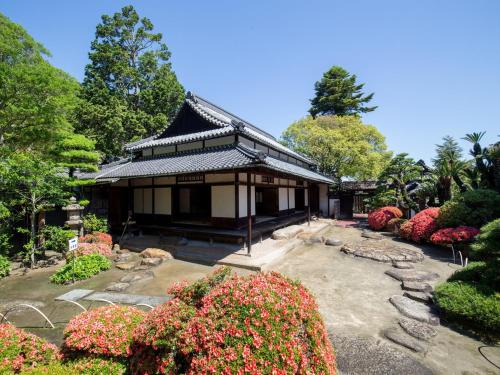 a building in a garden with flowers and trees at APA Hotel Kurashiki Ekimae in Kurashiki