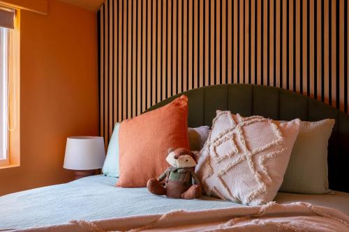 a teddy bear sitting on top of a bed with pillows at Broadway Scandi Chic Authentic Cottage in Broadway