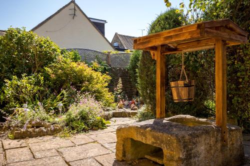 a garden with a bench and a wooden structure at Broadway Scandi Chic Authentic Cottage in Broadway