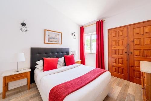 a bedroom with a bed with red curtains and a window at Monte Sao Pedro - Villa in Luz