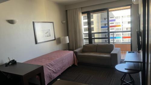 une chambre d'hôtel avec un lit, un canapé et une fenêtre dans l'établissement Hotel Bonaparte Flat Particular B, à Brasilia