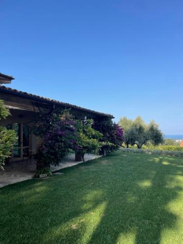 un cortile con prato verde, un edificio e alberi di La BouganVillea a Francavilla al Mare