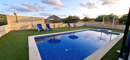 a swimming pool with chairs and umbrellas in a yard at Quinta Ribeirinha - Lagos in Lagos