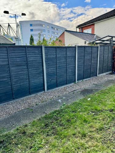 a fence with blue doors on the side of a road at Stylish & modern 2 bedroom City Centre Norwich Home in Norwich