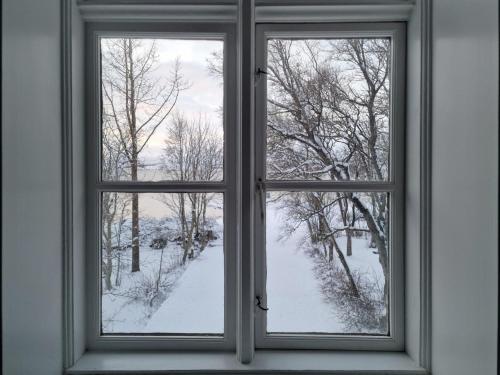 a window with a view of a snow covered yard at Gistihúsið - Lake Hotel Egilsstadir in Egilsstadir
