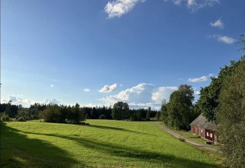 a large green field with a barn in the distance at Newly renovated cozy house Urshult-Åsnen-south Småland in Urshult