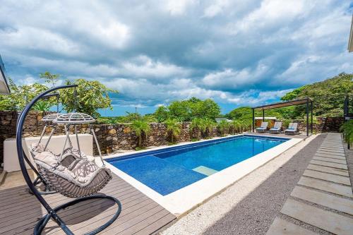 a swing on a deck next to a swimming pool at Villa Maravilla Estates, Tamarindo Beach, Prime Location, Family & Friends in Tamarindo