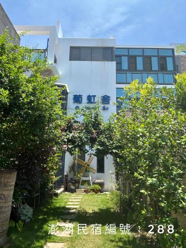 a white building with a garden in front of it at G Home Sir B&B in Magong