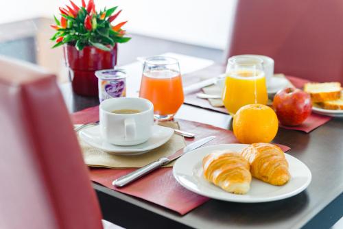 - une table avec petit-déjeuner composé de croissants et de jus d'orange dans l'établissement Lagrange Apart’Hotel Strasbourg Wilson, à Strasbourg