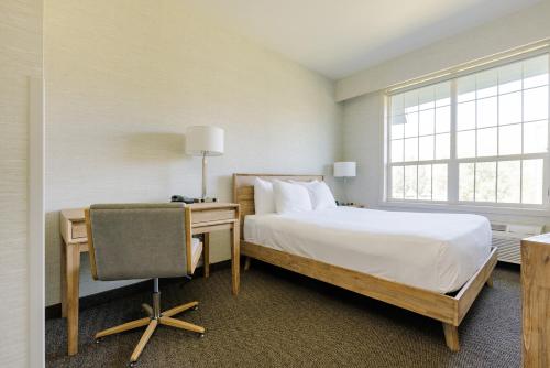 a bedroom with a bed and a desk with a chair at Balcomo, a Ramada by Wyndham in Penticton