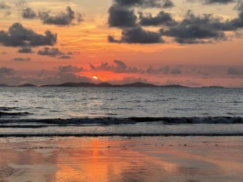 a sunset on a beach with the ocean at Oasis on Farnborough in Yeppoon