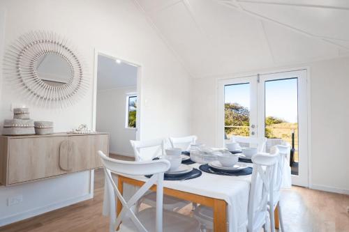 a white dining room with a table and white chairs at Oasis on Farnborough in Yeppoon