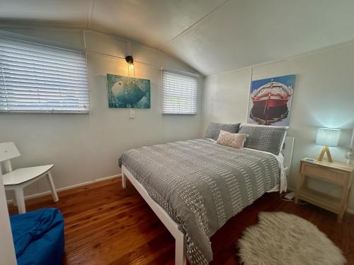 una camera con un letto e un tavolo e due finestre di Seaside Chalet Papamoa a Papamoa