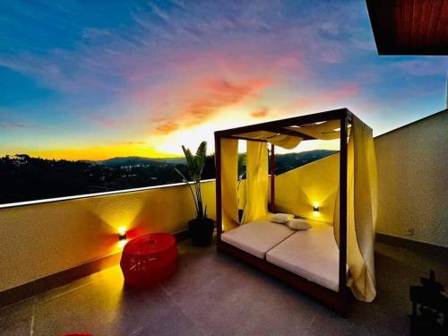 Apartamento com jacuzzi privativa no Wanderlust Hotel في كامبوس دو جورداو: سرير على شرفة مع غروب الشمس في الخلفية