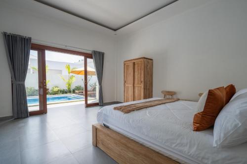 a bedroom with a bed and a view of a pool at Beatrix Villa in Ubud