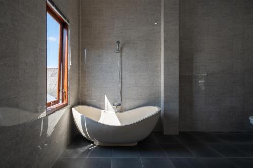 a white bath tub in a bathroom with a window at Beatrix Villa in Ubud