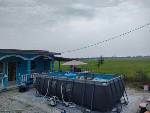 a woman in a pool in front of a house at Izz Homestay Sawah Padi Sungai Besar ! in Kampong Parit Ten