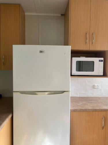 a white refrigerator in a kitchen with a microwave at Baudin Beach Holiday Units in Baudin Beach