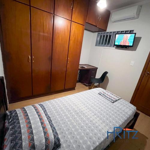 a bedroom with a bed and a cabinet and a tv at Ritz Hostel in Araçatuba