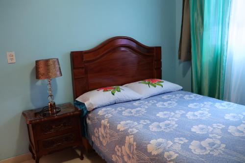 a bed with a wooden headboard and a table with a lamp at Casa céntrica en Morelia. in Morelia