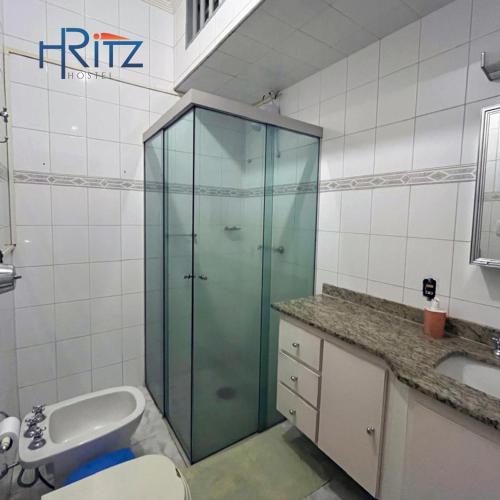 a bathroom with a glass shower with a toilet and a sink at Ritz Hostel in Araçatuba
