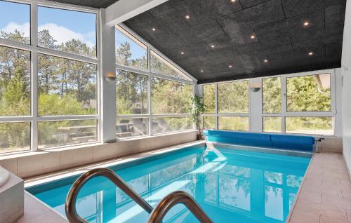 a swimming pool in a house with windows at Awesome Home In Ebeltoft With Sauna in Ebeltoft